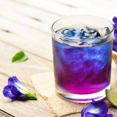 Butterfly pea or blue pea juice ice cool drink with lime on wooden table.