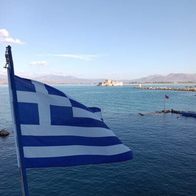 A Greek flag over the water in Nafplio, Greece
