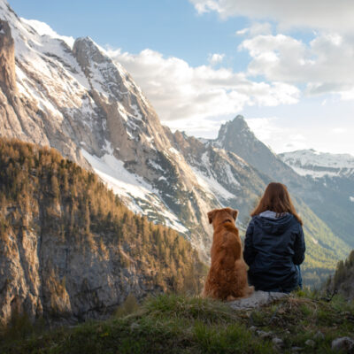 woman and dog sit looking out at mountains